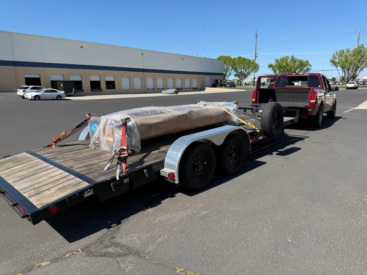 Wrapped cargo secured to a flatbed trailer outside a warehouse