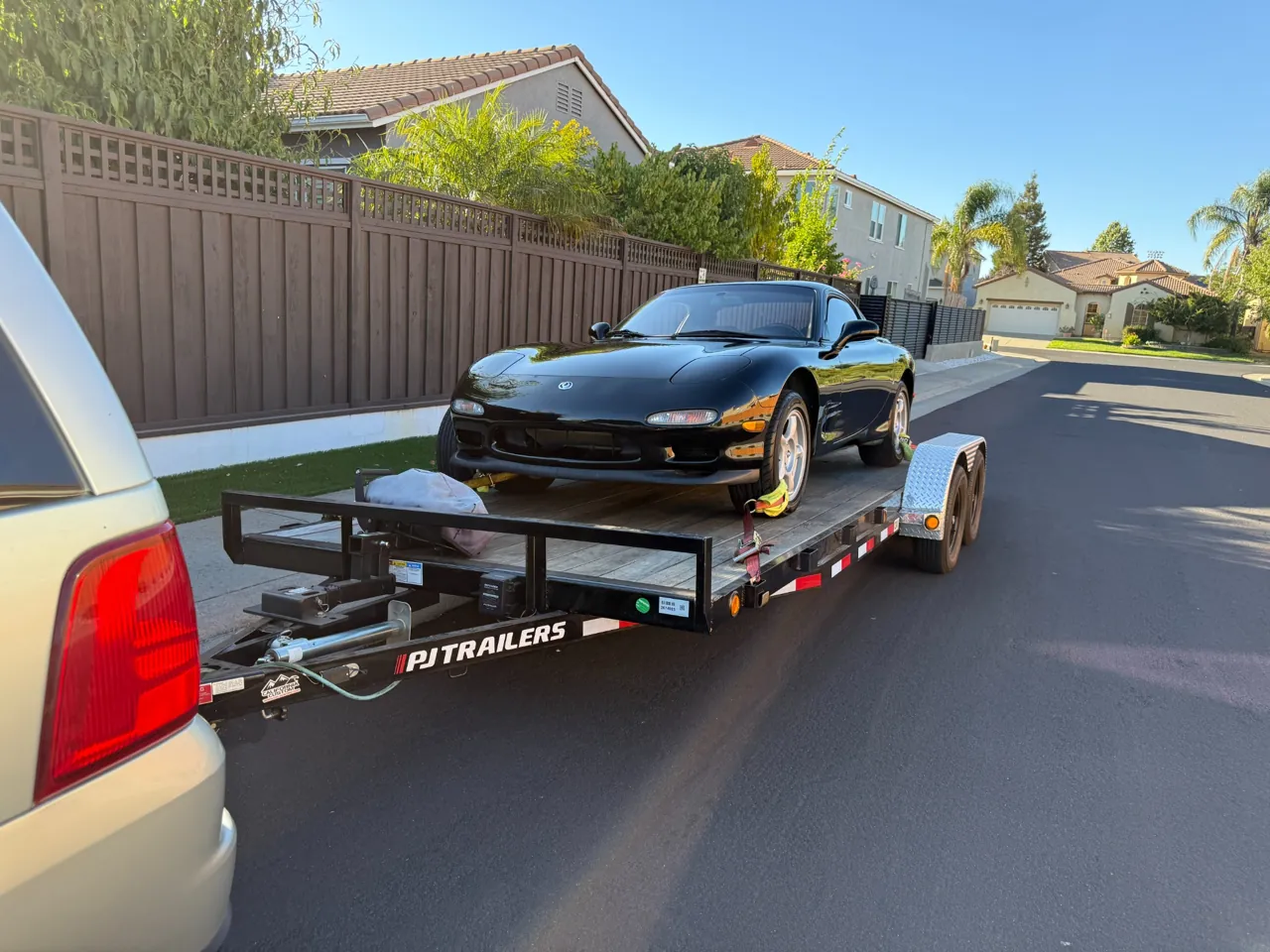 Black sports car loaded on a trailer on a residential street