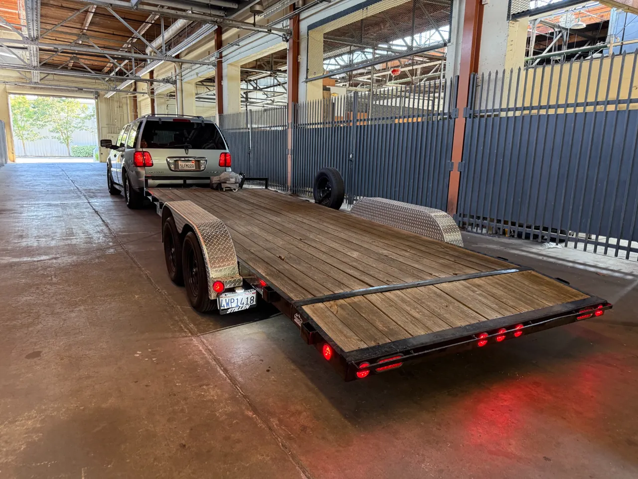 Empty wood-deck trailer attached to a pickup inside a covered facility